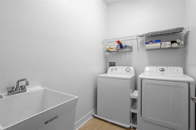 laundry room featuring light tile patterned flooring, laundry area, a sink, baseboards, and washer and dryer