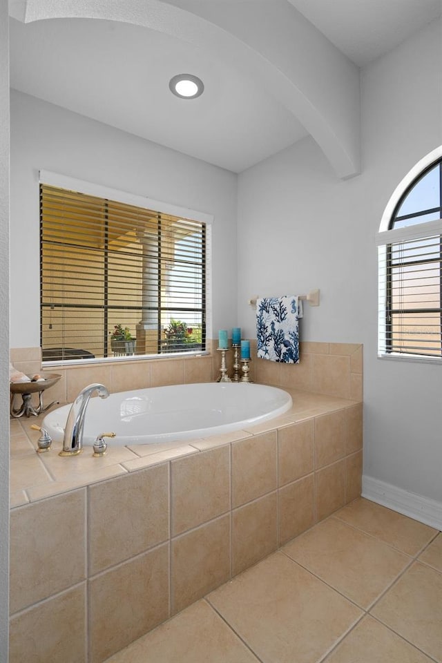 bathroom with a wealth of natural light, a garden tub, baseboards, and tile patterned floors