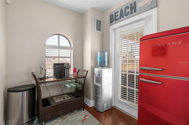 office with dark wood-type flooring, a wealth of natural light, visible vents, and baseboards