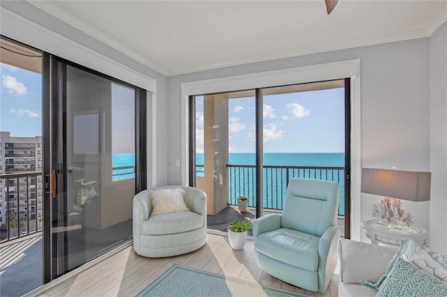 sitting room featuring ornamental molding, a water view, and wood finished floors