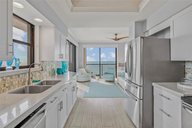 kitchen with decorative backsplash, dishwasher, a raised ceiling, light stone countertops, and a sink