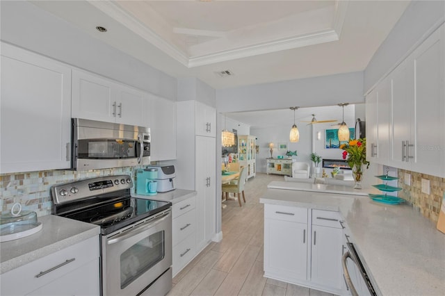 kitchen with stainless steel appliances, a raised ceiling, light countertops, visible vents, and white cabinetry