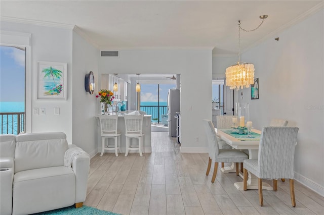 dining space featuring a notable chandelier, light wood-style flooring, visible vents, and crown molding