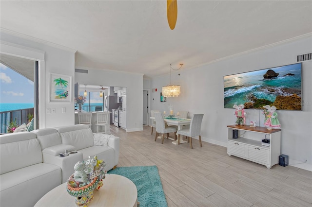 living area featuring crown molding, visible vents, a chandelier, light wood-type flooring, and baseboards