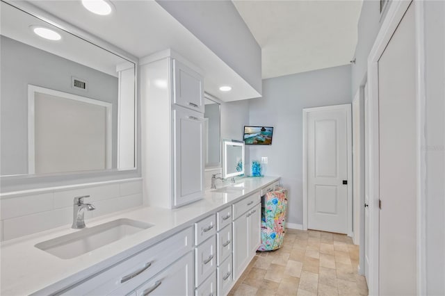 bathroom featuring visible vents, a sink, baseboards, and double vanity