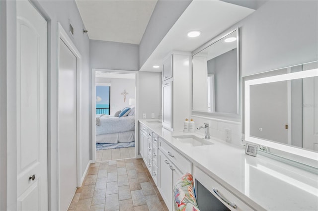 ensuite bathroom featuring double vanity, tasteful backsplash, ensuite bathroom, a sink, and recessed lighting