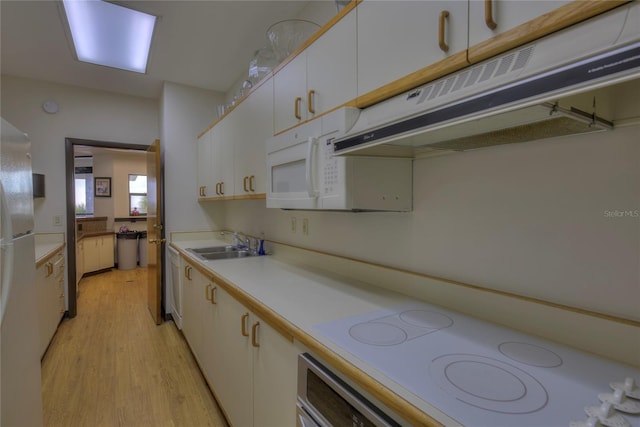 kitchen with light countertops, white cabinetry, a sink, white appliances, and under cabinet range hood