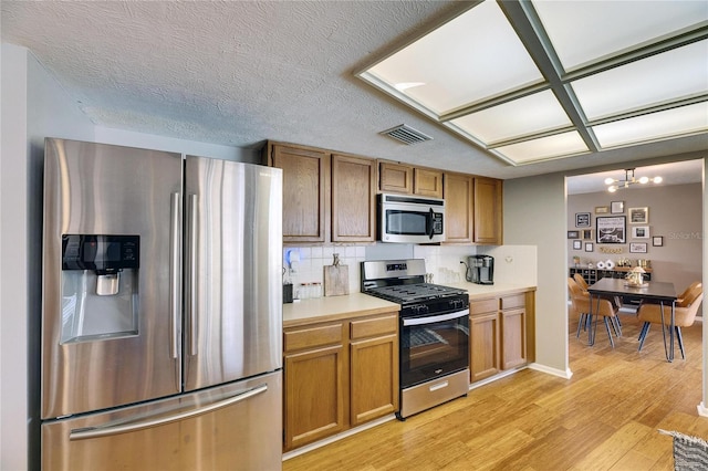 811 Eagle Ln, Apollo Beach, FL 33572 - kitchen with stainless steel appliances, light countertops, backsplash, a chandelier, and brown cabinets