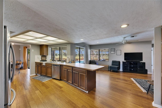 811 Eagle Ln, Apollo Beach, FL 33572 - kitchen with stainless steel appliances, a peninsula, a textured ceiling, open floor plan, and light wood-type flooring