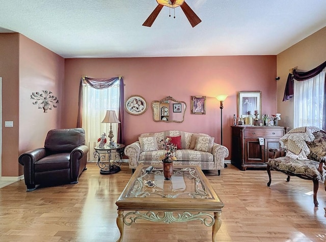 living area with a ceiling fan, plenty of natural light, and wood finished floors