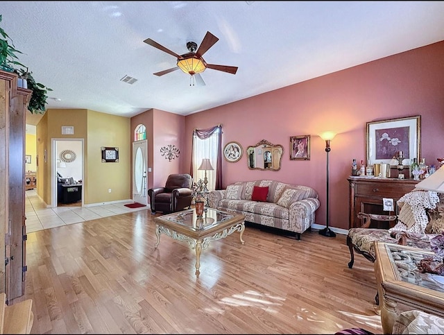 living area featuring light wood-type flooring, baseboards, and ceiling fan