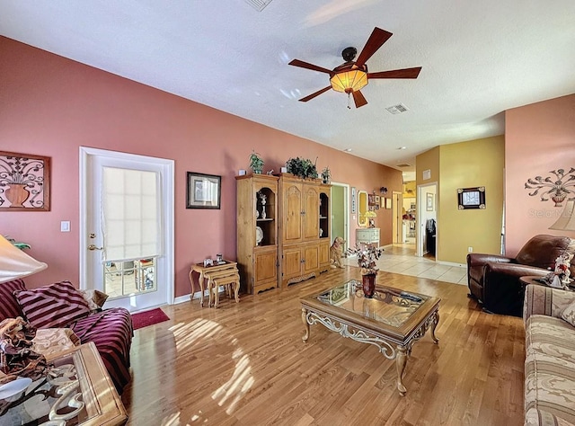 living room with visible vents, a textured ceiling, light wood finished floors, baseboards, and ceiling fan