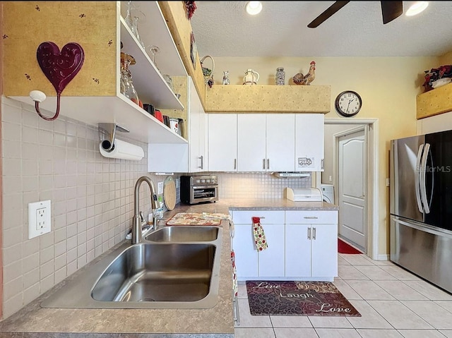 kitchen featuring backsplash, a toaster, freestanding refrigerator, white cabinets, and open shelves