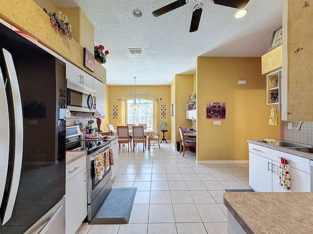 kitchen featuring visible vents, backsplash, light tile patterned floors, appliances with stainless steel finishes, and white cabinets