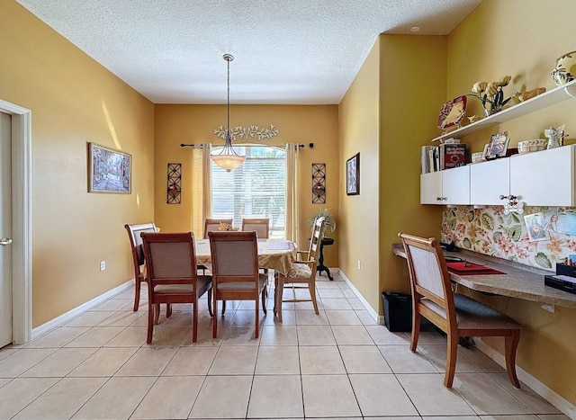 dining space featuring light tile patterned flooring, a textured ceiling, and baseboards