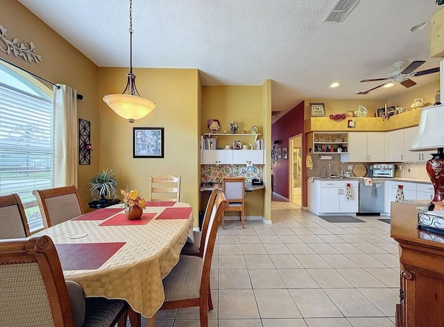 dining space with visible vents, a toaster, light tile patterned flooring, a textured ceiling, and a ceiling fan