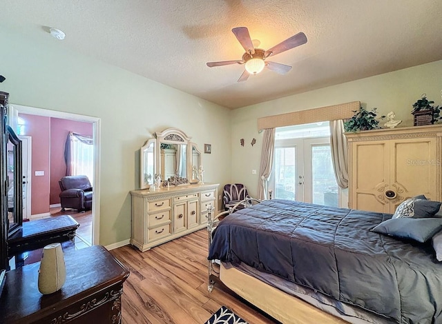 bedroom featuring ceiling fan, light wood-type flooring, french doors, a textured ceiling, and access to outside