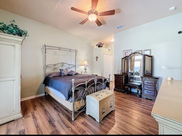 bedroom featuring wood finished floors, baseboards, visible vents, ceiling fan, and vaulted ceiling