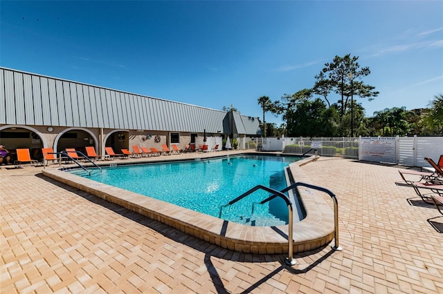 community pool with a patio area and fence