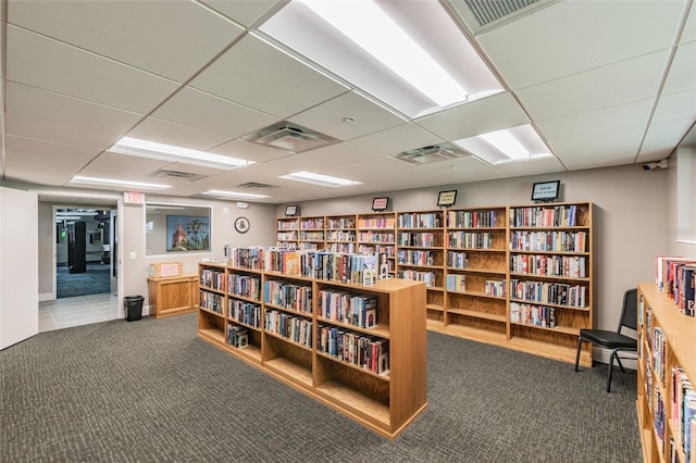 sitting room featuring carpet flooring, bookshelves, a paneled ceiling, and visible vents