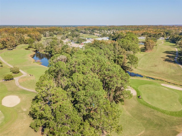 drone / aerial view featuring a wooded view, golf course view, and a water view