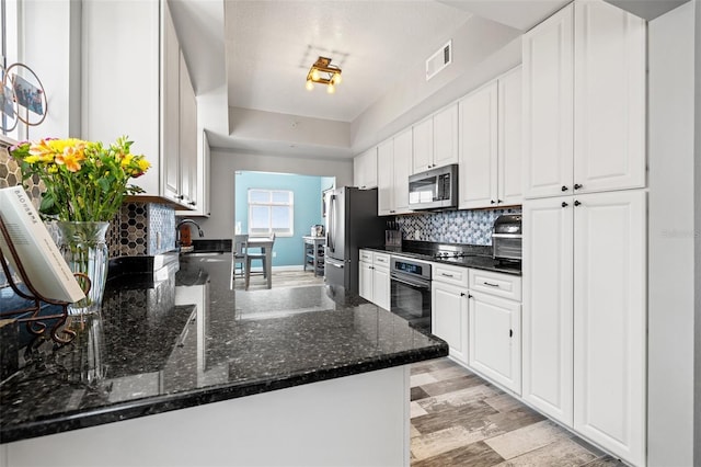 kitchen featuring black appliances, tasteful backsplash, visible vents, and white cabinets