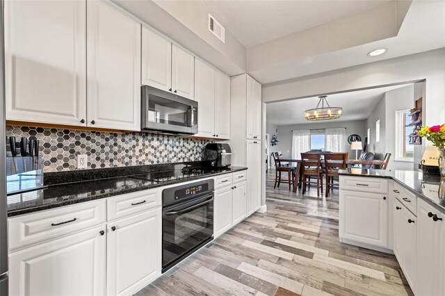 kitchen featuring light wood-style floors, visible vents, black appliances, and white cabinetry