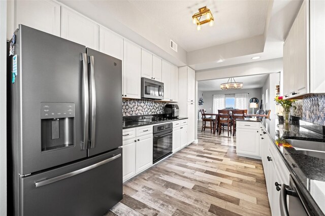 kitchen featuring black appliances, light wood-type flooring, backsplash, and white cabinets