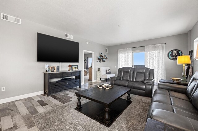 living room with a textured ceiling, visible vents, and baseboards