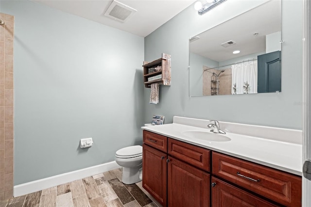 bathroom with toilet, wood finished floors, visible vents, baseboards, and tiled shower