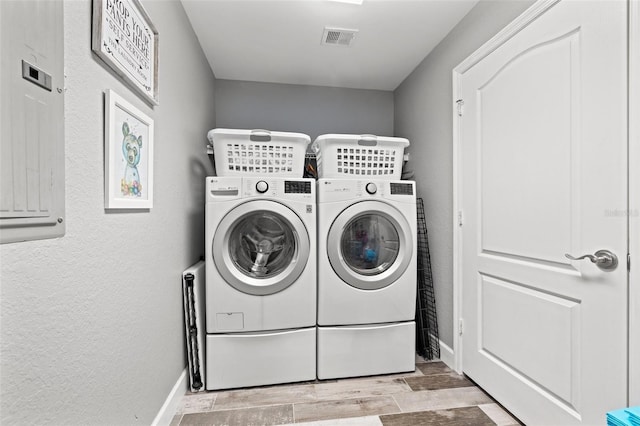 clothes washing area featuring laundry area, baseboards, visible vents, a textured wall, and washer and dryer
