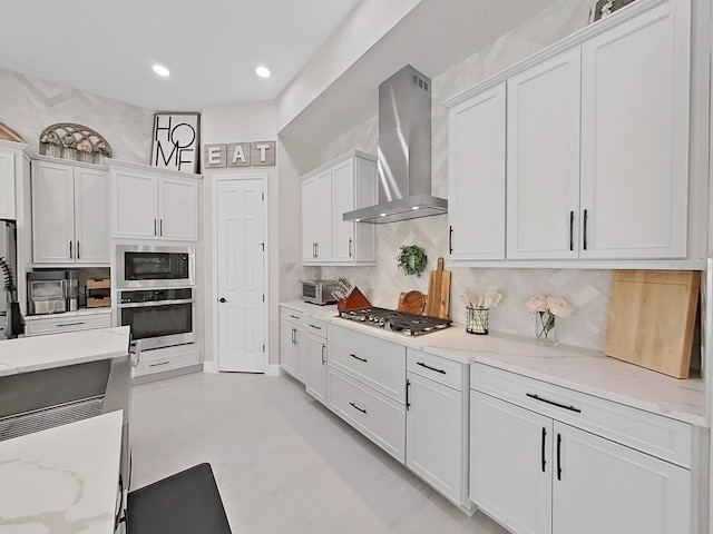 kitchen featuring black appliances, wall chimney range hood, white cabinets, and backsplash