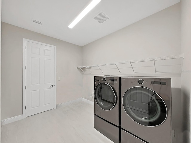 laundry area featuring laundry area, baseboards, visible vents, washer and dryer, and light wood-style floors