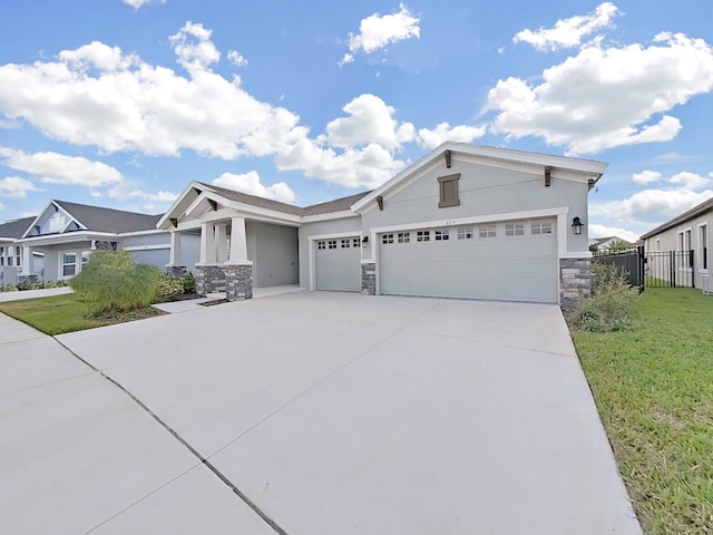 view of front of property featuring an attached garage, stone siding, driveway, stucco siding, and a front lawn