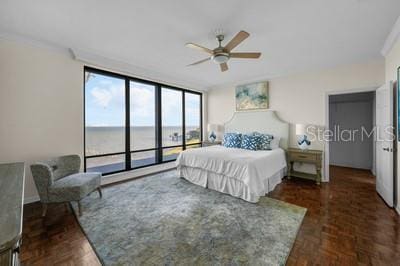 bedroom featuring floor to ceiling windows, a water view, dark parquet floors, access to outside, and ornamental molding