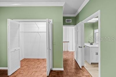 interior space with parquet flooring, vanity, and crown molding