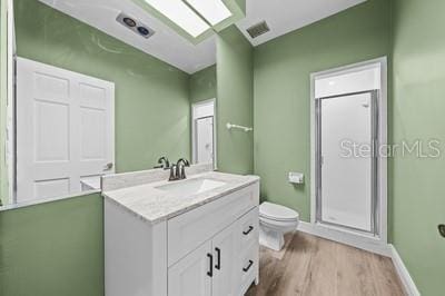 bathroom featuring vanity, walk in shower, toilet, and hardwood / wood-style floors