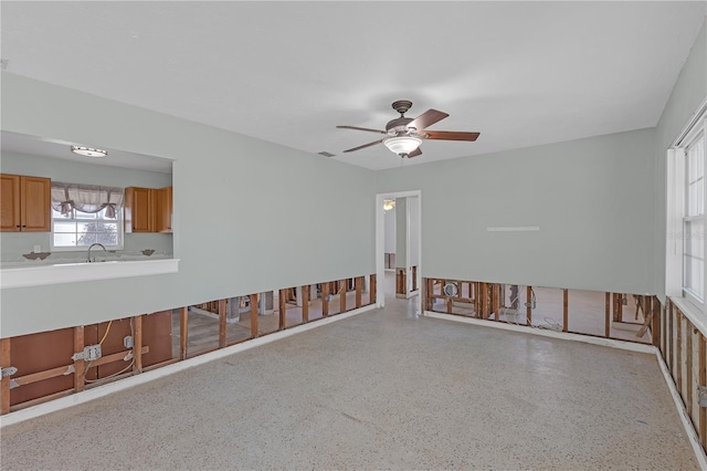 empty room featuring ceiling fan, light speckled floor, a sink, and visible vents