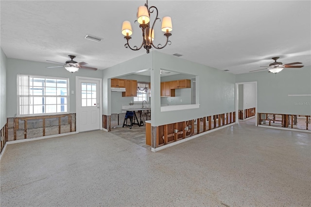 interior space with light speckled floor, ceiling fan with notable chandelier, a sink, and visible vents