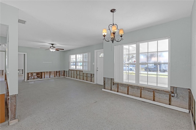 spare room with ceiling fan with notable chandelier, speckled floor, and visible vents