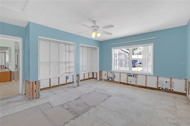 unfurnished bedroom featuring a ceiling fan and two closets