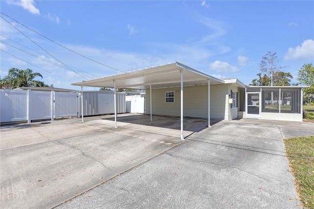 view of vehicle parking featuring a carport, driveway, and fence