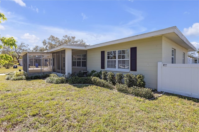 view of front of property featuring a front yard, fence, and a sunroom