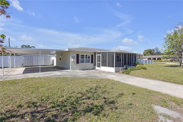 rear view of property featuring an attached carport, a sunroom, a yard, and fence