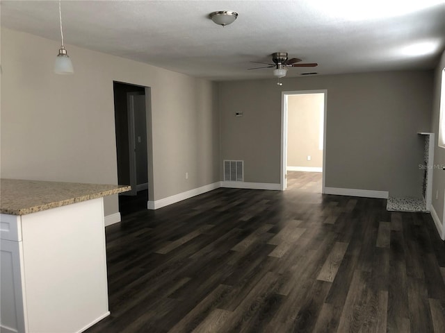 unfurnished living room with a ceiling fan, baseboards, visible vents, and dark wood-style flooring