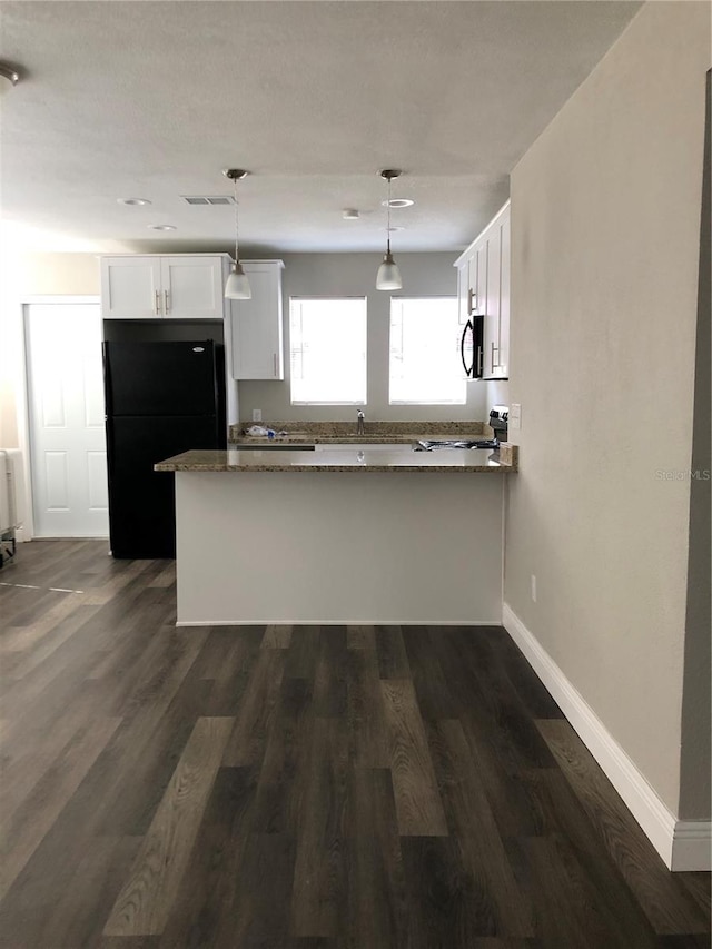 kitchen featuring dark wood finished floors, hanging light fixtures, freestanding refrigerator, white cabinets, and a peninsula