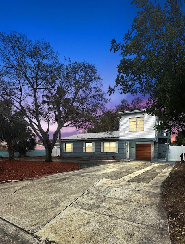 view of front of house with driveway, an attached garage, and fence