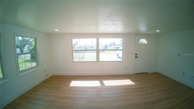 foyer entrance with a textured ceiling, light wood finished floors, recessed lighting, and baseboards