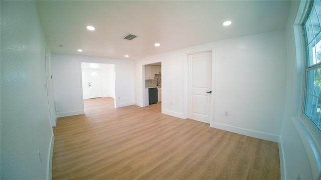 unfurnished room with baseboards, light wood-type flooring, visible vents, and recessed lighting