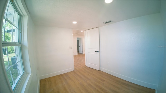 spare room with light wood finished floors, recessed lighting, visible vents, and baseboards